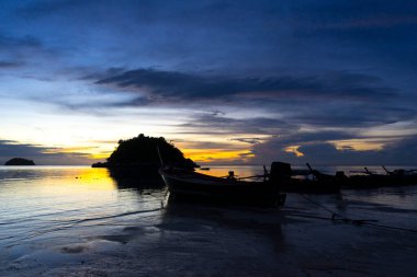 Koh Lipe Adası, Satun, Tayland 'da gün batımında tropikal sahilde tekne siluetleri.