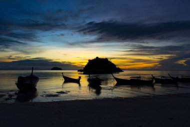 Koh Lipe Adası, Satun, Tayland 'da gün batımında tropikal sahilde tekne siluetleri.