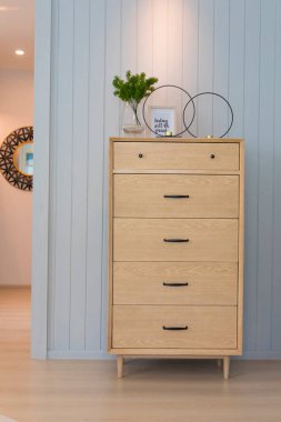 Odasında ahşap bir çekmece ve mavi ahşap bir duvar var..