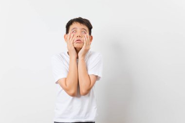 Asyalı çocuk beyaz arka planda asık suratlı ve komik bir ifade takınıyor..