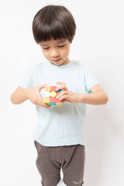 Asyalı şirin çocuk beyaz arka planda rubik ile oynuyor..