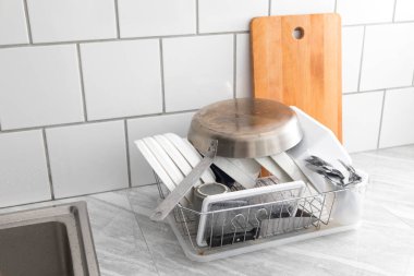 Yeni yıkanmış bulaşıklar, tabaklar, bardaklar, kavanozlar, bardaklar, çatal bıçak takımı, kurumayı bekleyen tavalar. Ev halkı kavramı ve günlük hayatta yardımcılar.