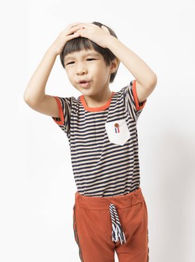 Asyalı çocuk baş ağrısı çekiyor ve ellerini başına bastırıyor. Acı dolu bir jestle. Beyaz arkaplanda izole. 