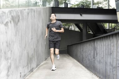 Etkin adam modern binanın duvarı boyunca çalışan spor giyim