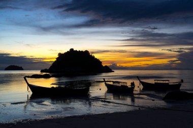 Koh Lipe Adası, Satun, Tayland 'da gün batımında tropikal sahilde tekne siluetleri.