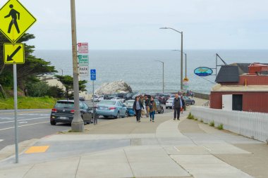 Trafik işaretleri ve deniz kıyısında yürüyen insanlar.