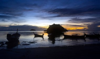 Koh Lipe Adası, Satun, Tayland 'da gün batımında tropikal sahilde tekne siluetleri.
