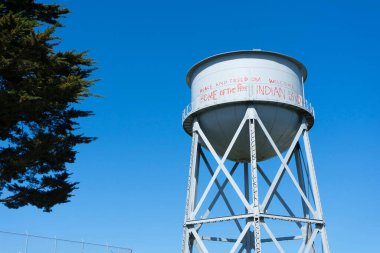 Mavi gökyüzü olan paslı metal bir tank.