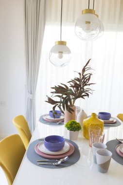 Masada pembe ve mor tabaklar olan güzel bir masa. Akşam yemeği için cam eşyalar ve çatal bıçaklar..