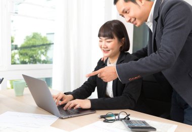 Kadın çalışırken ve yazarken erkeğin eli bilgisayarı işaret ederken..