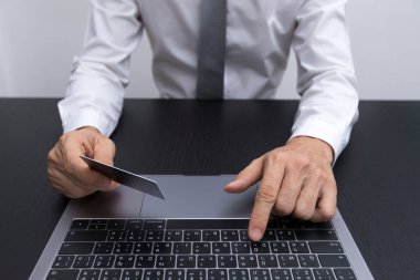 Beyaz gömlekli, akıllı telefonuna bakıp, masanın üstünde dizüstü bilgisayar kullanan iyi giyimli bir adamın ellerini yakın plan çek..