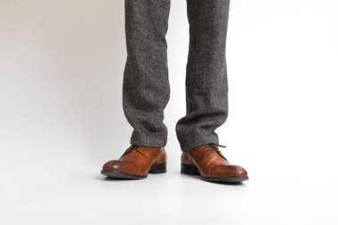 Deri ayakkabılı adam beyaz arka planda duruyor.