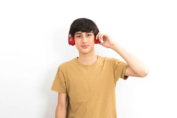 彼の頭の上にヘッドフォンを持つ10代の男の子は白い背景に音楽を聴く — ストック写真