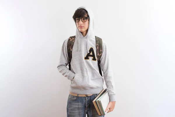 英俊的少年学生背着背包 手里拿着书本 手指着白底站着 — 图库照片