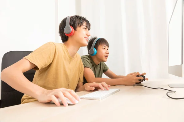 Два Подростка Наушниками Использующими Компьютеры Играть Онлайн Игры Дома Счастливый — стоковое фото