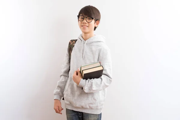亚洲少年学生背着背包 手里拿着书本 指指点点地站在白色背景上 — 图库照片