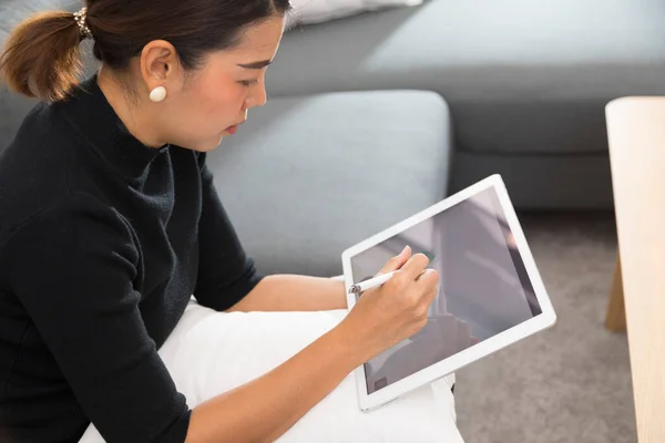 若いアジアの女性はソファの上でリラックスし 自宅でデジタルタブレットを見て — ストック写真