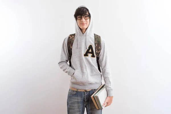 英俊的少年学生背着背包 手里拿着书本 手指着白底站着 — 图库照片