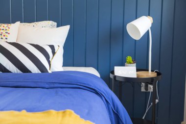 Mavi ve sarı yastıklı şık bir yatak odası..