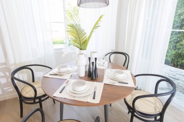 Yuvarlak ahşap masa ve siyah sandalyeli modern yemek odası.