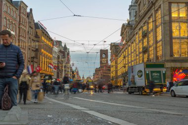 Amsterdam, Hollanda - 29 Kasım 2019: Arka planda tramvayla Baraj Meydanı 'nda yürüyen kimliği belirsiz kişiler