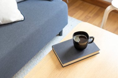 cup of coffee and book on sofa in living room interior