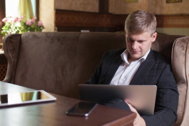 Akıllı telefon ve defter compu kullanarak evden çalışan genç adam