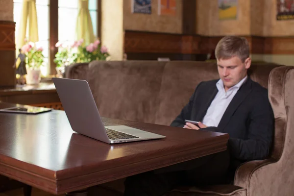 Jovem trabalhando em casa usando telefone inteligente e notebook compu — Fotografia de Stock