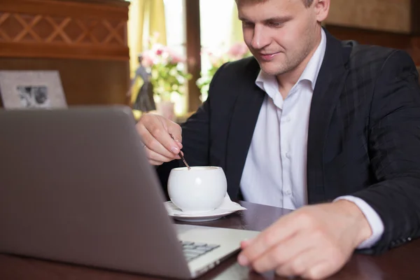 Negócios, tecnologia. Jovem trabalhando em um laptop com uma caneca o — Fotografia de Stock