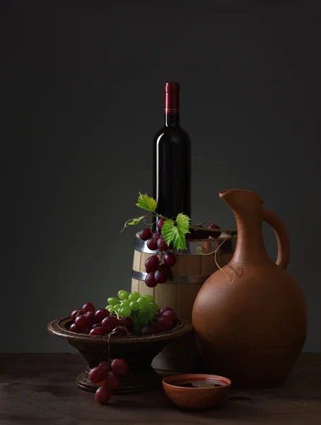 Butelka czerwonego wina, winogron i drewniane beczki — Zdjęcie stockowe