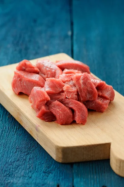 Raw lean meat cuts on wooden board on deep blue background