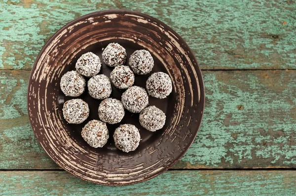 Homemade raw vegan sweets in coconut shavings in ceramic plate o