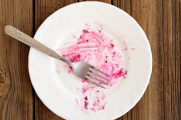 Empty white plate and fork with traces of eaten blackberry pie