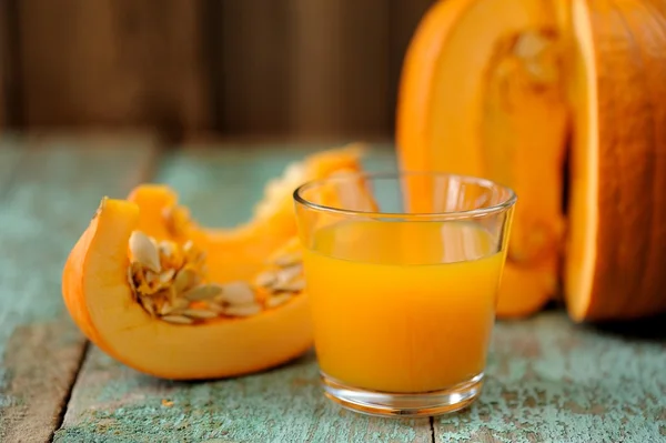 Glass of bright sweet pumpkin juice and cut pumpkin with seeds o