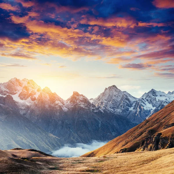 Paisaje otoñal y picos nevados de montaña. Puesta de sol fantástica . —  Fotos de Stock