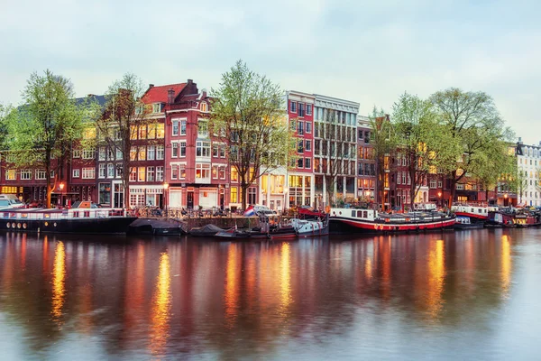 Casas de canal de Amsterdã ao entardecer com reflexos vibrantes — Fotografia de Stock