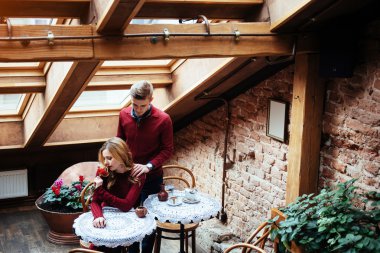 Güzel genç adam ve kadın Sevgililer günü restoranda kutluyoruz. Adam bir gül kız arkadaşına veriyor