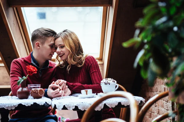 美しい若い男性と女性は レストランでバレンタインデーを祝っています 男は彼のガール フレンドにバラを与えています — ストック写真