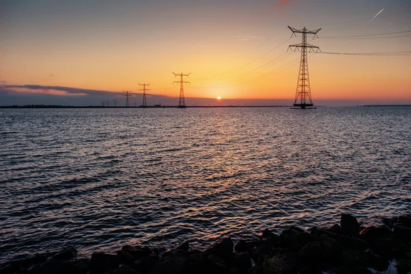 Línea eléctrica sobre el agua durante una fantástica puesta de sol . —  Fotos de Stock