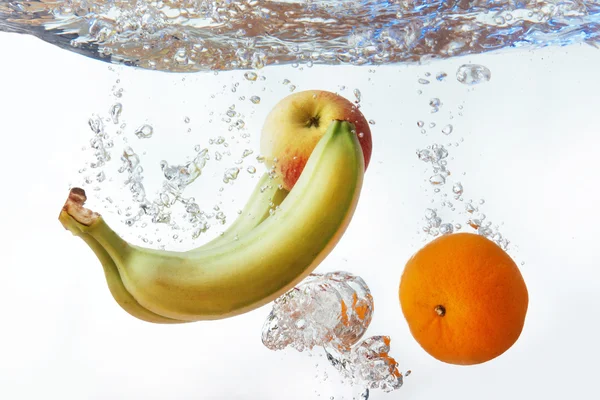 Bananas e laranjas e uma maçã caíram na água — Fotografia de Stock