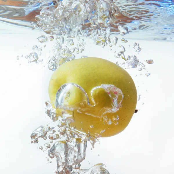 Πράσινο μήλο κάτω από το νερό με ένα ίχνος από διαφανείς φυσαλίδες. — Φωτογραφία Αρχείου