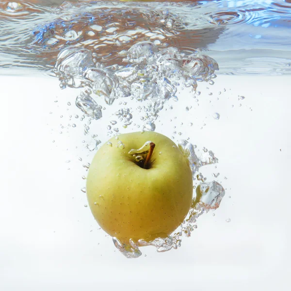 Grüner Apfel unter Wasser mit einer Spur transparenter Blasen. — Stockfoto