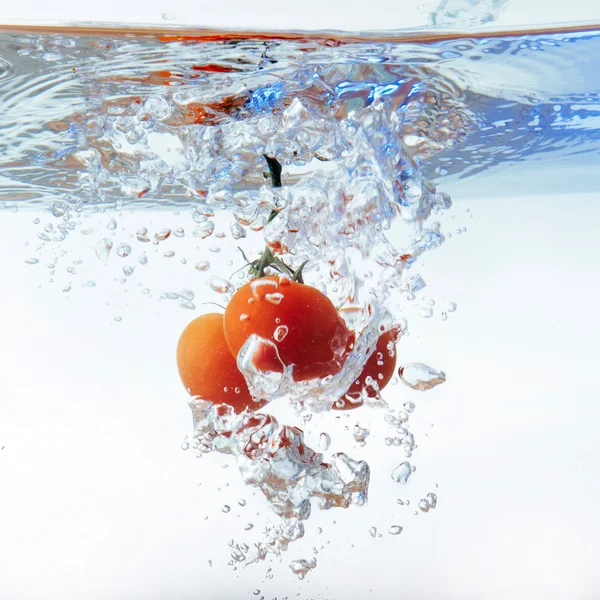 Tomates cereja frescos com respingo de água isolado — Fotografia de Stock