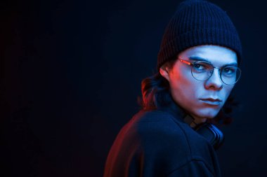 Modaya uygun bir adam. Stüdyo karanlık stüdyoda neon ışıkla çekiliyor. Ciddi bir adamın portresi..