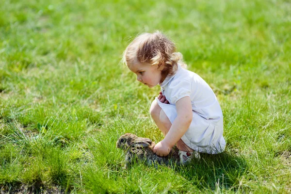 Kind met een konijn op het gras — Stockfoto