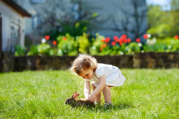 Kind met een konijn op het gras — Stockfoto