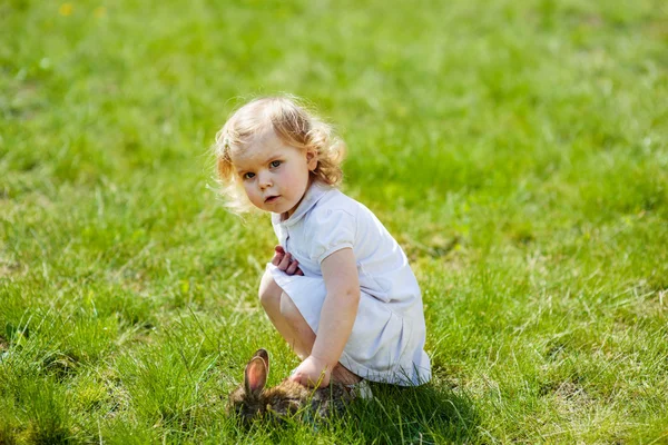 Kind met een konijn op het gras — Stockfoto