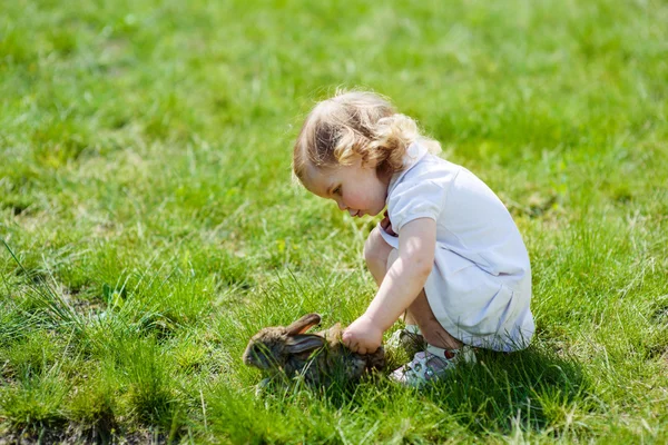 Kind met een konijn op het gras — Stockfoto