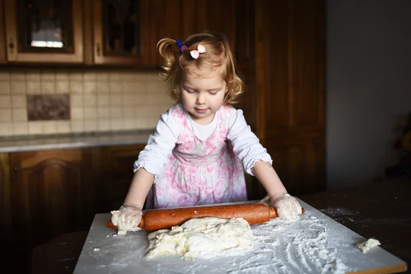 Smiling little girl kneading the dough — Stock Photo, Image
