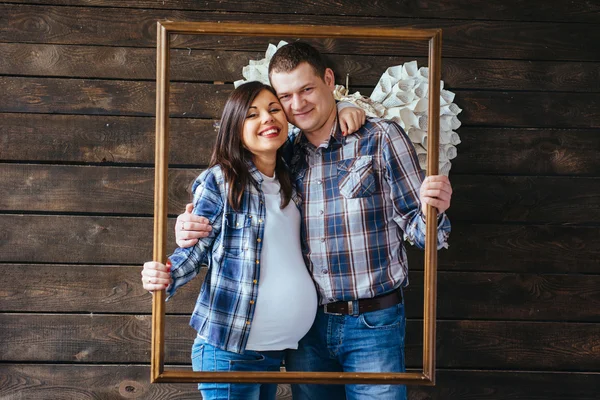 Famiglia felice in attesa di bambino guardando attraverso un'immagine cornice . — Foto Stock